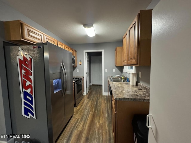 kitchen with sink, dark wood-type flooring, stainless steel appliances, and a textured ceiling