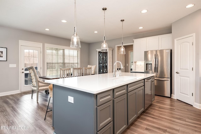 kitchen with pendant lighting, sink, gray cabinetry, a kitchen island with sink, and stainless steel appliances