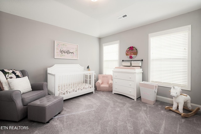 bedroom featuring a nursery area and light colored carpet