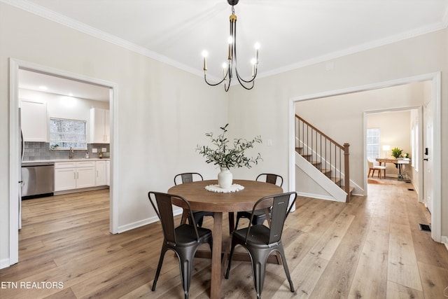 dining space featuring crown molding, an inviting chandelier, and light hardwood / wood-style flooring