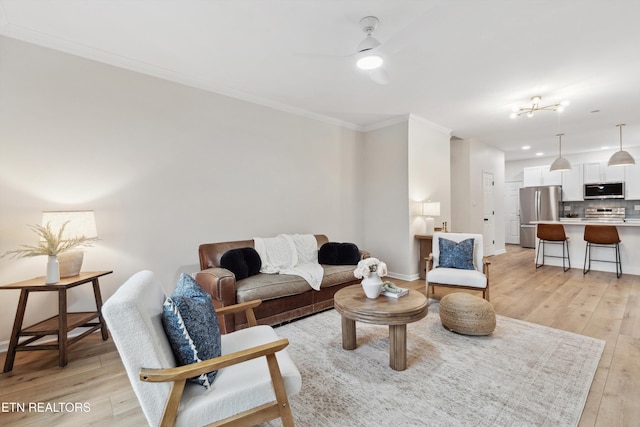 living room with ceiling fan, ornamental molding, and light hardwood / wood-style floors