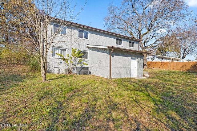 rear view of house featuring cooling unit and a lawn