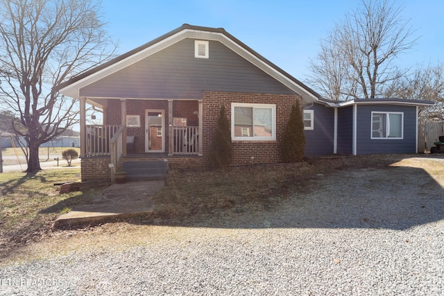 bungalow with covered porch, brick siding, and driveway