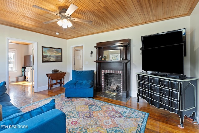 living area featuring ornamental molding, a fireplace, wood finished floors, and wood ceiling