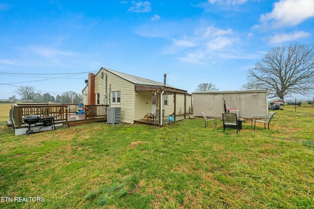 rear view of house featuring central AC unit, a deck, and a lawn