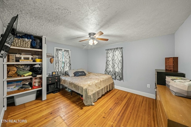 bedroom with ceiling fan, hardwood / wood-style floors, and a textured ceiling