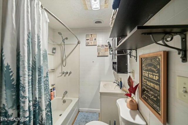 full bathroom featuring toilet, a textured ceiling, tile walls, vanity, and shower / bath combination with curtain