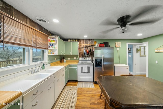 kitchen featuring sink, white electric range, refrigerator, green cabinets, and stainless steel refrigerator with ice dispenser