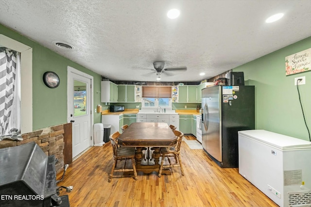 dining room with sink, a textured ceiling, ceiling fan, and light hardwood / wood-style flooring