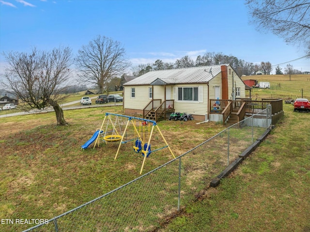 rear view of house featuring a yard and a playground