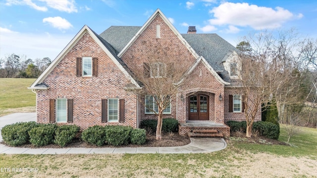 tudor home with a front lawn and french doors