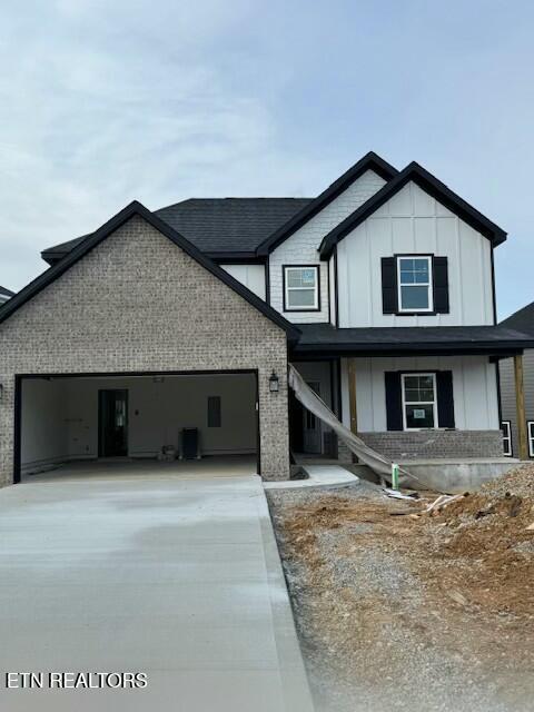 view of front of property with driveway, central AC unit, an attached garage, board and batten siding, and brick siding