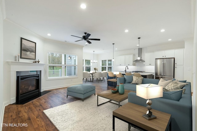 living area featuring dark wood-style floors, recessed lighting, a fireplace with flush hearth, and crown molding