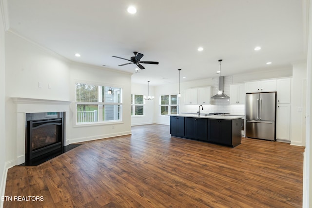 kitchen with freestanding refrigerator, open floor plan, white cabinetry, and wall chimney range hood