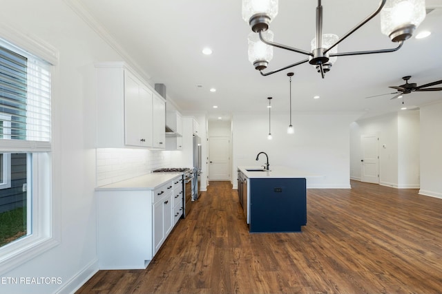 kitchen featuring light countertops, decorative backsplash, appliances with stainless steel finishes, open floor plan, and a sink