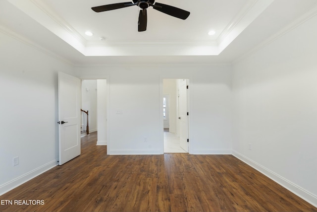 unfurnished bedroom featuring baseboards, hardwood / wood-style floors, a raised ceiling, and crown molding