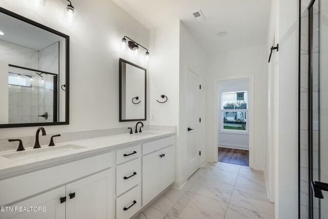 bathroom featuring a stall shower, marble finish floor, a sink, and double vanity