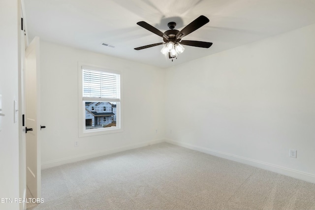 carpeted empty room with visible vents, baseboards, and ceiling fan