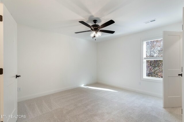 spare room with carpet floors, visible vents, ceiling fan, and baseboards