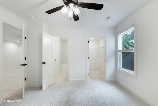 unfurnished bedroom with carpet floors, visible vents, a spacious closet, and baseboards