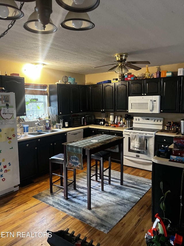 kitchen with sink, white appliances, ceiling fan, and light wood-type flooring