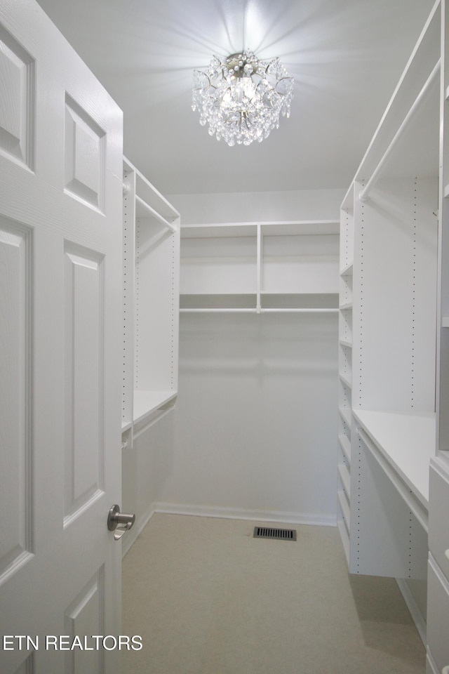 spacious closet featuring a chandelier and carpet floors