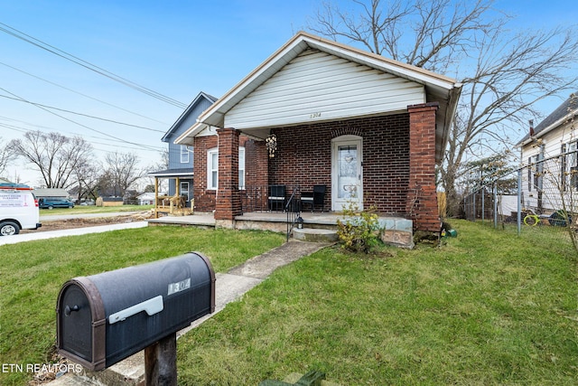 view of front facade with covered porch, brick siding, and a front yard