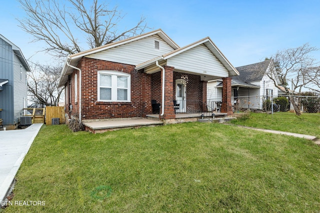 bungalow-style home with a front yard, covered porch, brick siding, and fence