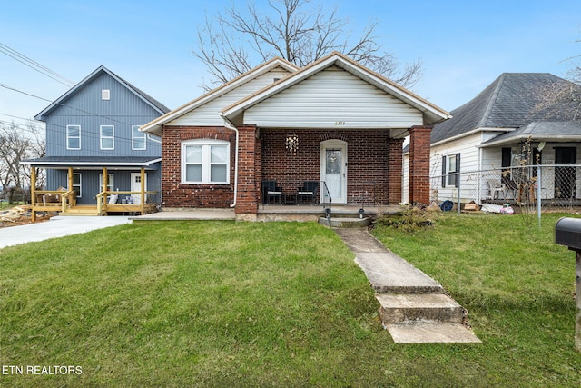 view of front facade featuring covered porch, a front lawn, and brick siding