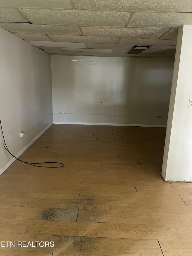 basement featuring a paneled ceiling and hardwood / wood-style floors