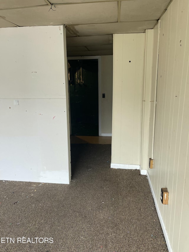 carpeted spare room featuring wood walls