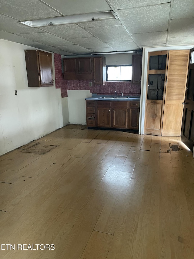 kitchen with sink, a drop ceiling, light hardwood / wood-style floors, and dark brown cabinetry