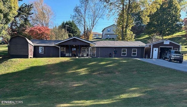 view of front of house featuring a garage, an outdoor structure, a front yard, and covered porch