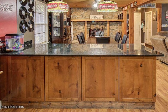 bar with pendant lighting, light wood-type flooring, and dark stone counters