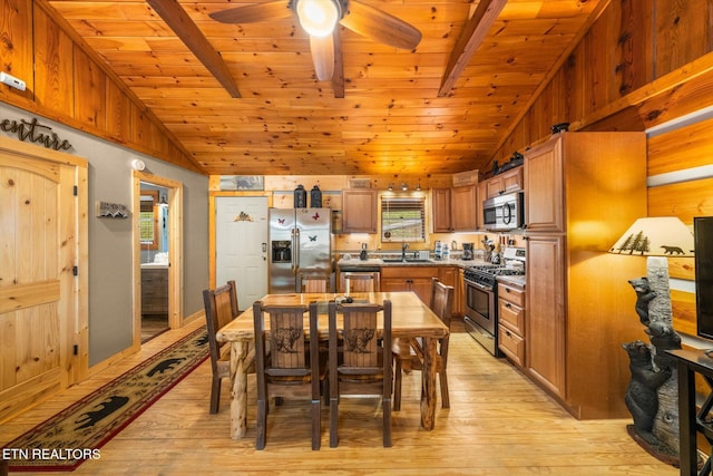 dining space featuring sink, lofted ceiling with beams, and light wood-type flooring