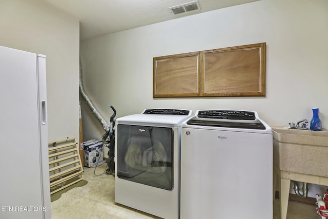 laundry room with cabinets, separate washer and dryer, and sink