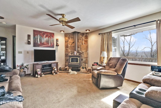 living room with a wood stove, light colored carpet, a textured ceiling, and ceiling fan