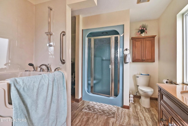 bathroom featuring a shower with door, vanity, and toilet