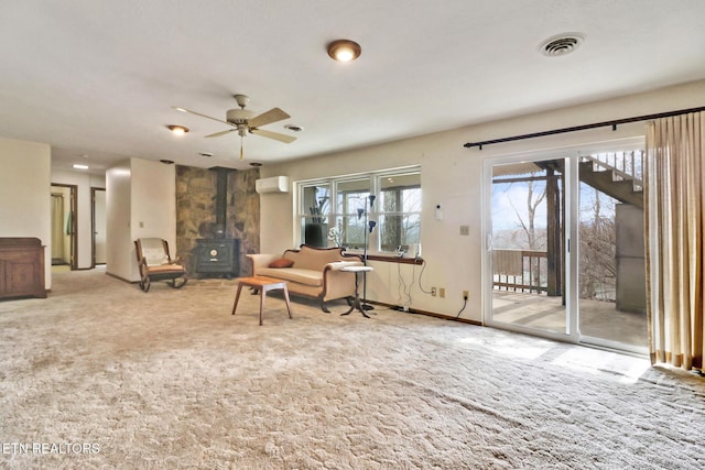 carpeted living room featuring ceiling fan, a wall mounted AC, and a wood stove