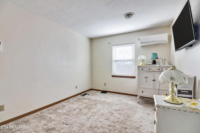 unfurnished bedroom featuring light carpet, a wall unit AC, and a textured ceiling