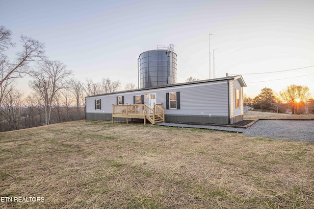 back of property at dusk featuring a yard and a deck