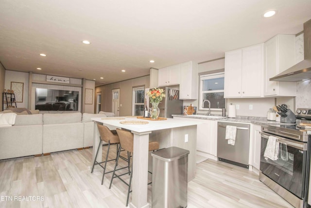 kitchen with white cabinets, stainless steel appliances, and wall chimney exhaust hood