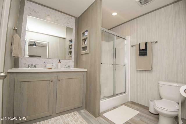 bathroom with visible vents, a sink, toilet, and a shower with shower door