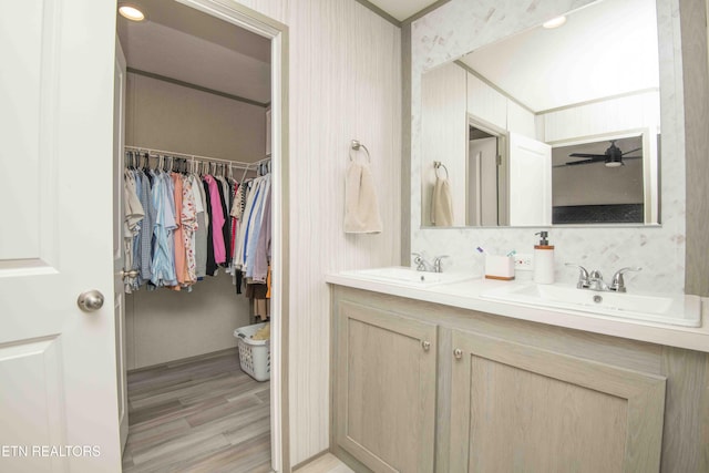 bathroom with double vanity, wood finished floors, a ceiling fan, and a sink