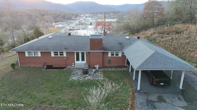 rear view of house featuring a mountain view, a yard, a carport, and french doors