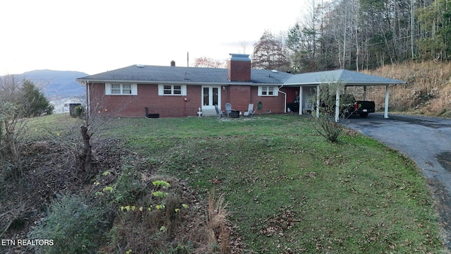 rear view of property with a carport, a yard, and a mountain view