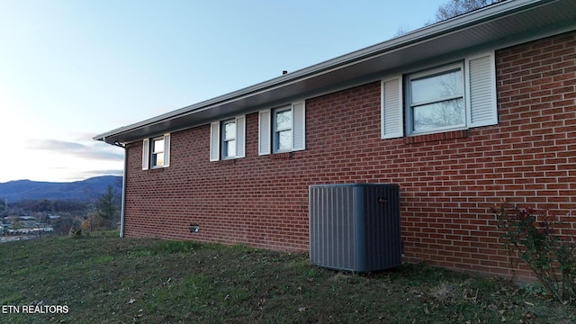 view of side of property featuring cooling unit, a mountain view, and a lawn