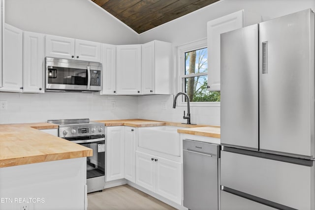 kitchen featuring butcher block counters, stainless steel appliances, and white cabinets