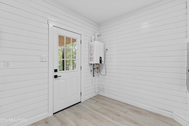 doorway featuring light hardwood / wood-style floors, water heater, and wood walls