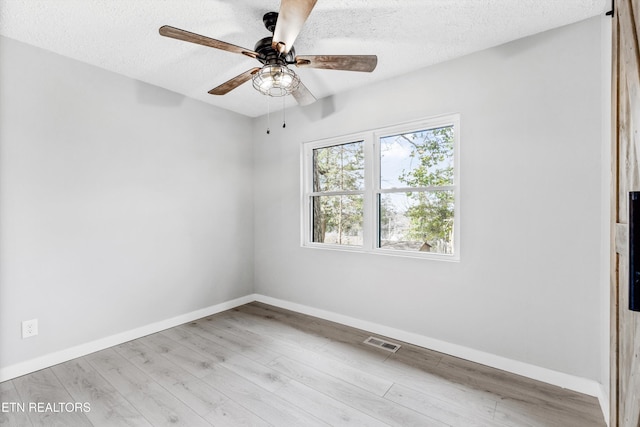 unfurnished room with ceiling fan, a healthy amount of sunlight, light hardwood / wood-style floors, and a textured ceiling